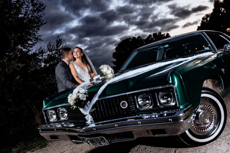 Novios junto a auto vintage al atardecer